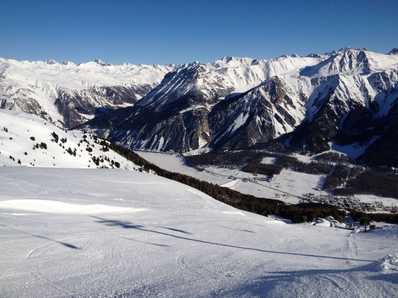 Auf den Pisten der Haideralm.
Bei dem schneebedeckten Stausee im Tal handelt es sich um den Reschensee (Reschenpass).
